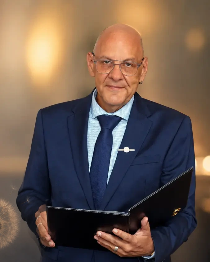Trauerredner Carsten Riedel mit Redemappe vor warmem, unscharfem Hintergrund und einer dezenten Pusteblume