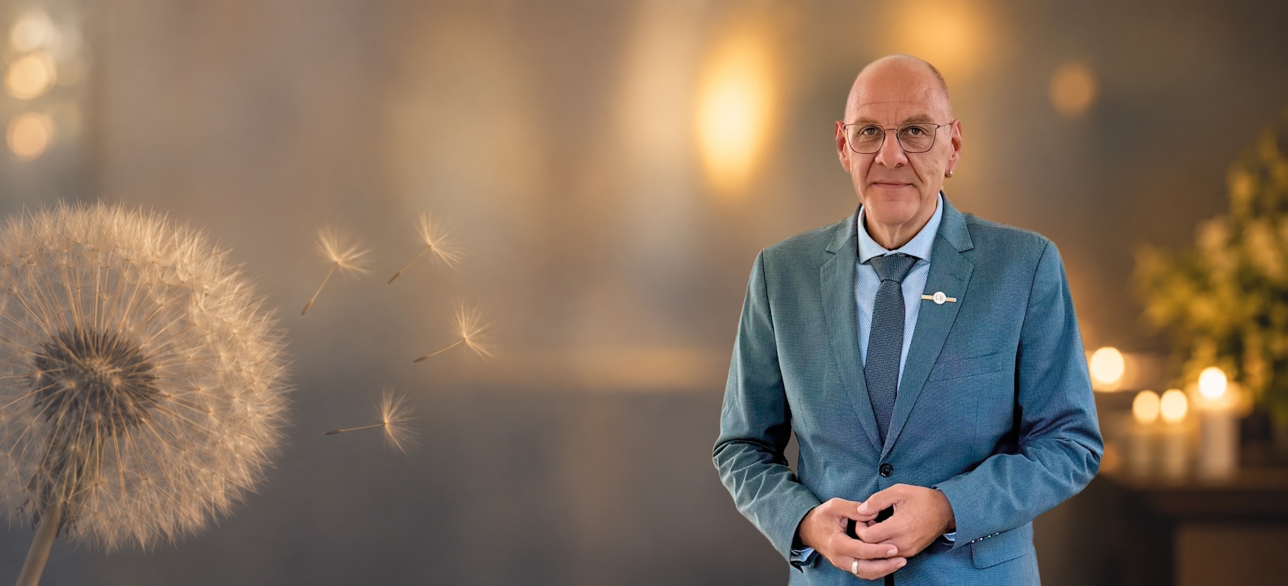 Trauerredner Carsten Riedel mit Redemappe vor warmem, unscharfem Hintergrund und einer dezenten Pusteblume